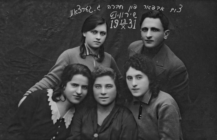 Cuatro muchachas y un muchacho posan juntos en un estudio; arriba, una dedicatoria manuscrita en ídish y la fecha 13 X 1931.